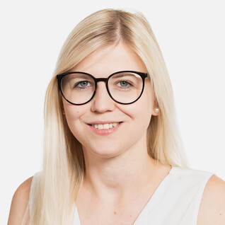 Frau mit langen blonden Haaren, Brille und Lächeln.